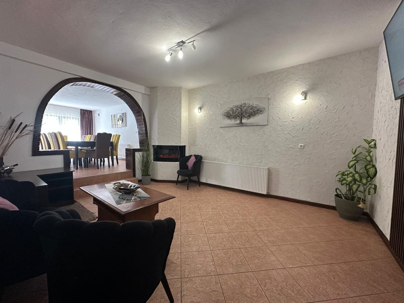 Livingul cu șemineu și arcada de lemn spre sala de mese
